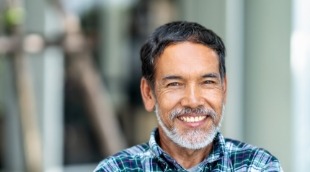 Man in plaid shirt grinning outdoors